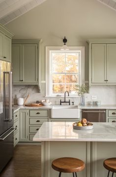 a kitchen with green cabinets and white counter tops