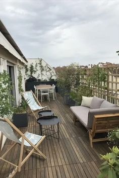 a wooden deck with chairs and tables next to a patio area that has potted plants on it