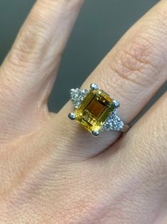 a woman's hand with a yellow and white diamond ring on top of it