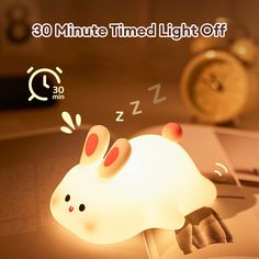 an alarm clock is sitting on top of a table with a light up rabbit lamp