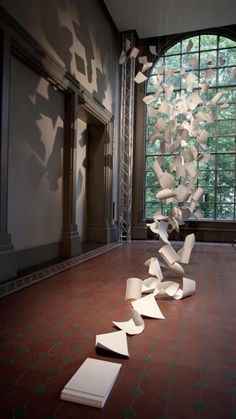 an art exhibit with paper falling from the ceiling