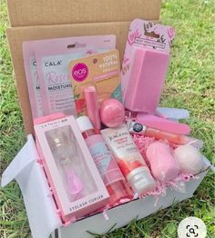 an open box with pink items in it on the grass next to a cardboard box