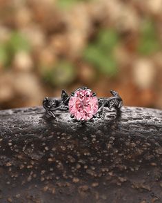 a pink diamond ring sitting on top of a rock