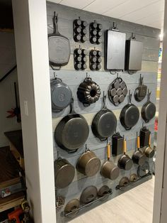 an assortment of pots and pans hanging on a wall