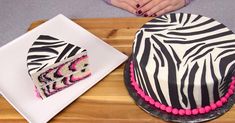 a zebra print cake sitting on top of a wooden cutting board next to a slice of cake