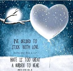 a heart - shaped balloon floating in the air next to a tree branch with snow falling on it