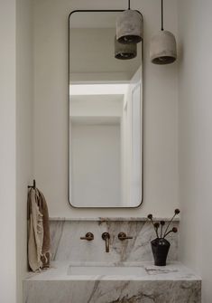 a bathroom with marble counter tops and a large mirror above the sink, along with two hanging lights