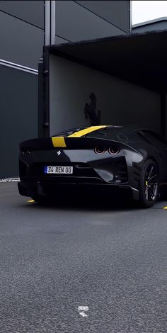 a black and yellow sports car is parked in front of a building with an open door