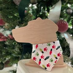 a dog bandana hanging from the top of a christmas ornament in front of a tree