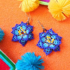 Embrace nature's bloom with our Huichol Beaded Flower Earrings🌺. Expertly handcrafted by one of our partner Huichol artisans, these earrings radiate with vibrant bead patterns, reflecting the beauty of blossoming flowers. They're a must-have for those looking to add a splash of color and cultural charm to their ensemble. Dive into the world of Huichol craftsmanship and let your style flourish！ ◆Symbols in Huichol Jewelry◆ Flowers: They are sacred and used in the healing process and Huichol cele Blue Handmade Spiritual Earrings, Handmade Blue Spiritual Earrings, Handmade Traditional Flower Earrings For Festivals, Traditional Handmade Flower Earrings For Festivals, Floral Jewelry For Celebrations, Handmade Traditional Flower Earrings, Traditional Handmade Flower Beaded Earrings, Bohemian Beaded Earrings In Flower Shape, Bohemian Beaded Earrings In Flower Shape For Gifts