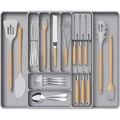 an assortment of kitchen utensils and spoons in a gray tray on a white background