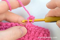 two hands crocheting the end of a piece of pink yarn with a yellow crochet hook