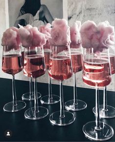 five wine glasses filled with pink liquid and cotton floss