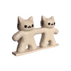 two white ceramic cats holding each other