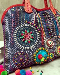 a colorful handbag sitting on top of a table next to pom poms