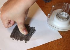 a person is using a brush to clean the surface of a paper with a blender in the background