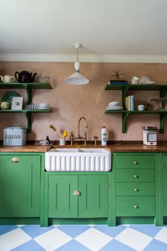 a kitchen with green cabinets and shelves filled with dishes on top of the counter tops