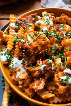 a yellow bowl filled with pasta and meat covered in sour cream, garnished with chives