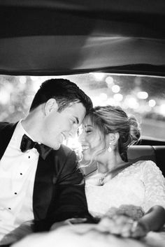 a bride and groom sitting in the back seat of a car