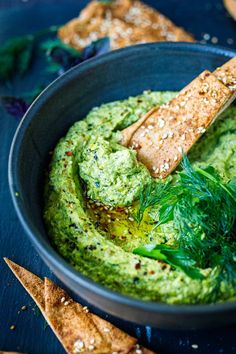 a black bowl filled with guacamole and bread sticks