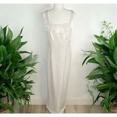 a white dress on a mannequin next to plants