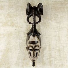 an african mask hanging on the wall in front of a white background with black accents