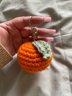 a crocheted orange keychain being held by a person's hand