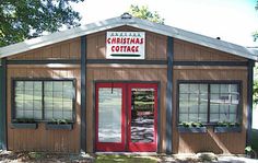 a small building with two windows and a sign on the door that says christmas cottage