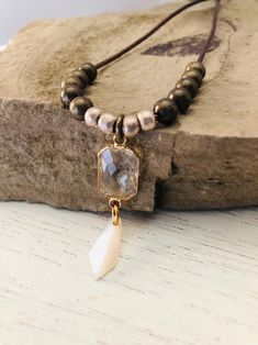 This neutral boho necklace has a rich brown genuine leather cord.   Strung on the leather are classic bronze brass beads as well as intricately handmade silver African brass beads.  It's focal point contains a luxe faceted crystal pendant accompanied by a simple, yet refined, mother of pearl bead.  This piece expresses femininity with a modern rustic style.  The cord measures 26 inches and the pendant is 1 3/4 inches in length. Bohemian Adjustable Faceted Crystal Necklaces, Modern Rustic Style, African Brass Beads, Boho Necklaces, Neutral Boho, Brass Beads, Jewelry Stand, Faceted Crystal, Boho Necklace