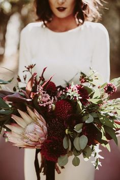 a woman holding a bouquet of flowers on her wedding day