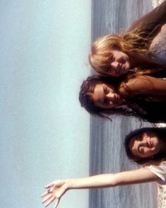 three women standing next to each other near the ocean