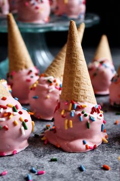 pink ice cream cones with sprinkles are on the table next to other desserts