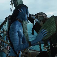 two people dressed as avatars on a boat in the ocean, one with his face painted blue