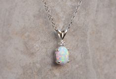 "Gorgeous pairing of a white opal and CZ accent gemstone. The gemstones are handset into a sterling silver pendant and hung from a sterling silver chain. This white opal has amazing flashes of color when it catches the light. The resulting necklace is stunning yet simple, a truly elegant necklace! The necklace ships in a lovely gift box ready to give as a gift or keep for yourself! Pictured with cubic zirconia accent stone color: \"White / Clear - April\" Setting Material - 925 Sterling Silver C Silver Opal Birthstone Jewelry, White Gold Opal Necklace For Gift, White Gold Opal Necklace As Gift, White Opal Birthstone Jewelry, White Ethiopian Opal Jewelry For Anniversary, Elegant White Pink Opal Jewelry, White Oval Opal Necklace, White Ethiopian Opal Gemstone Jewelry, White Opal Necklace For Gift