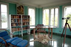 a dog laying on the floor in front of a table and chairs with bookshelves