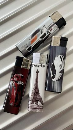 four different types of lighters sitting on top of a white surface with the eiffel tower in the background