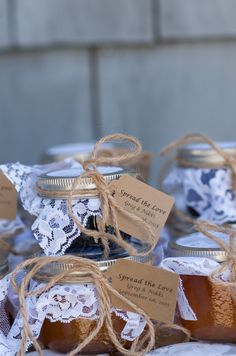 jars filled with honey sitting on top of a white table cloth covered in twine lace