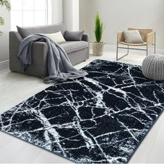 a black and white rug in a living room next to a couch, chair and potted plant