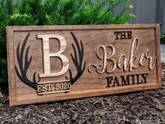 a wooden sign that says the baker family on it in front of some plants and bushes