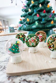 a wooden board topped with christmas decorations on top of a counter next to a tree