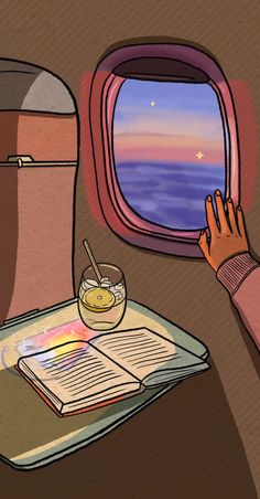 an airplane window with a book and cup on the table next to it, looking out at the ocean