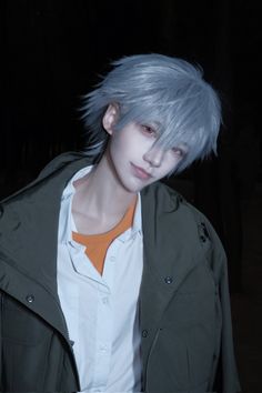 a man with grey hair and an orange tie standing in front of a dark background