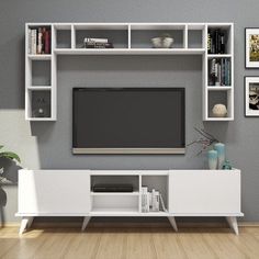 a white entertainment center with bookshelves and a flat screen tv mounted on the wall