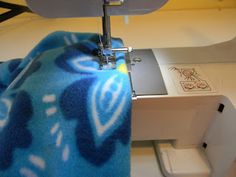 a blue and white blanket is being sewn on a sewing machine with the needle pointing up