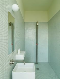 a white sink sitting under a bathroom mirror next to a faucet mounted on a wall