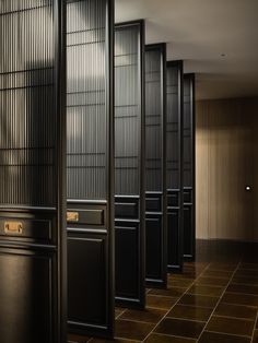 a row of black doors sitting next to each other on top of a tiled floor