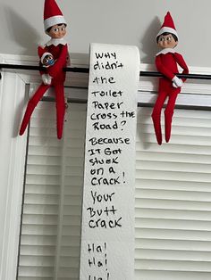 two elfs are hanging on the wall next to a sign