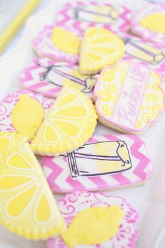 some decorated cookies are sitting on a table with yellow and pink decorations in the shape of lemons