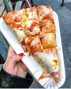 a person holding a white tray with slices of pizza on it