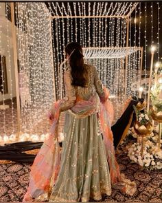 a woman standing in front of a decorated stage with lights on the walls and decorations around her